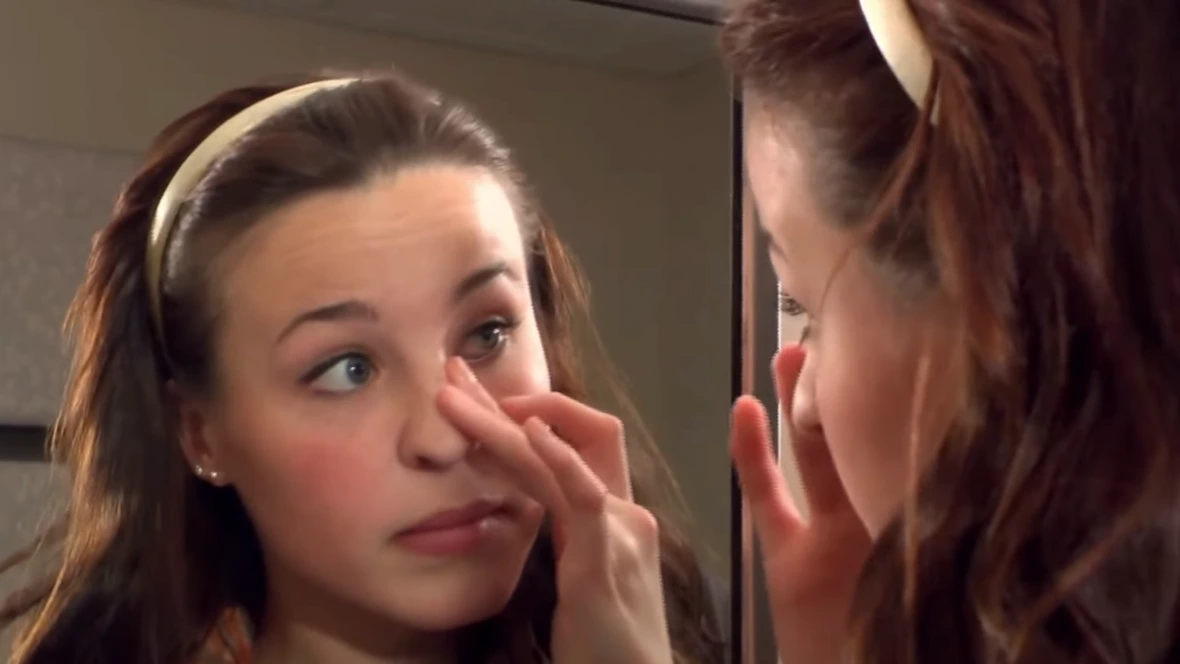 Girl looking at her face in the mirror